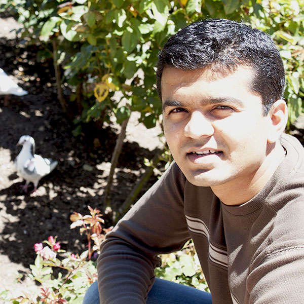 Jinesh in front of white pigeon next to a rose plant